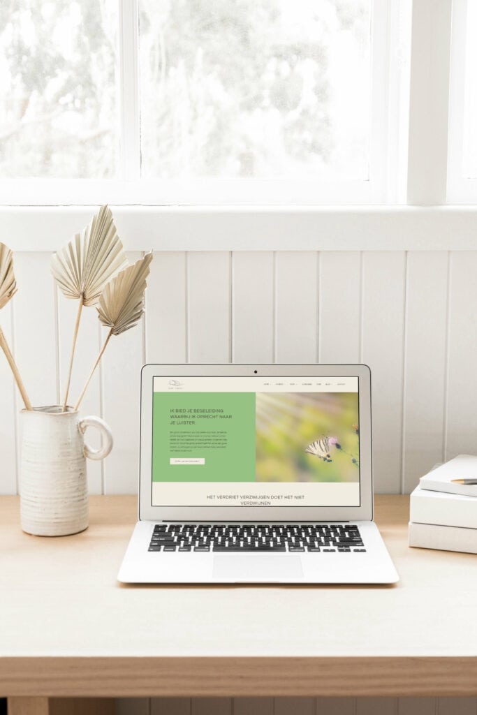 Laptop met Nederlandse begeleidingswebsite op houten bureau